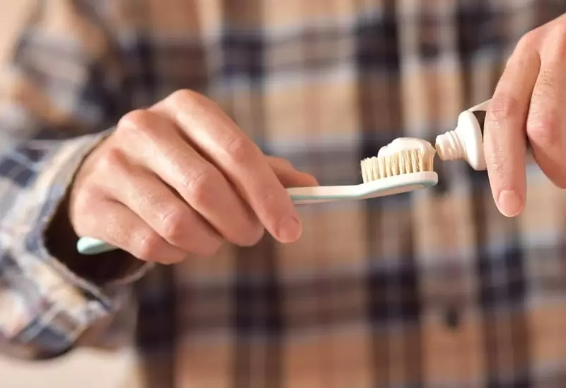 Young man applying toothpaste on toothbrush